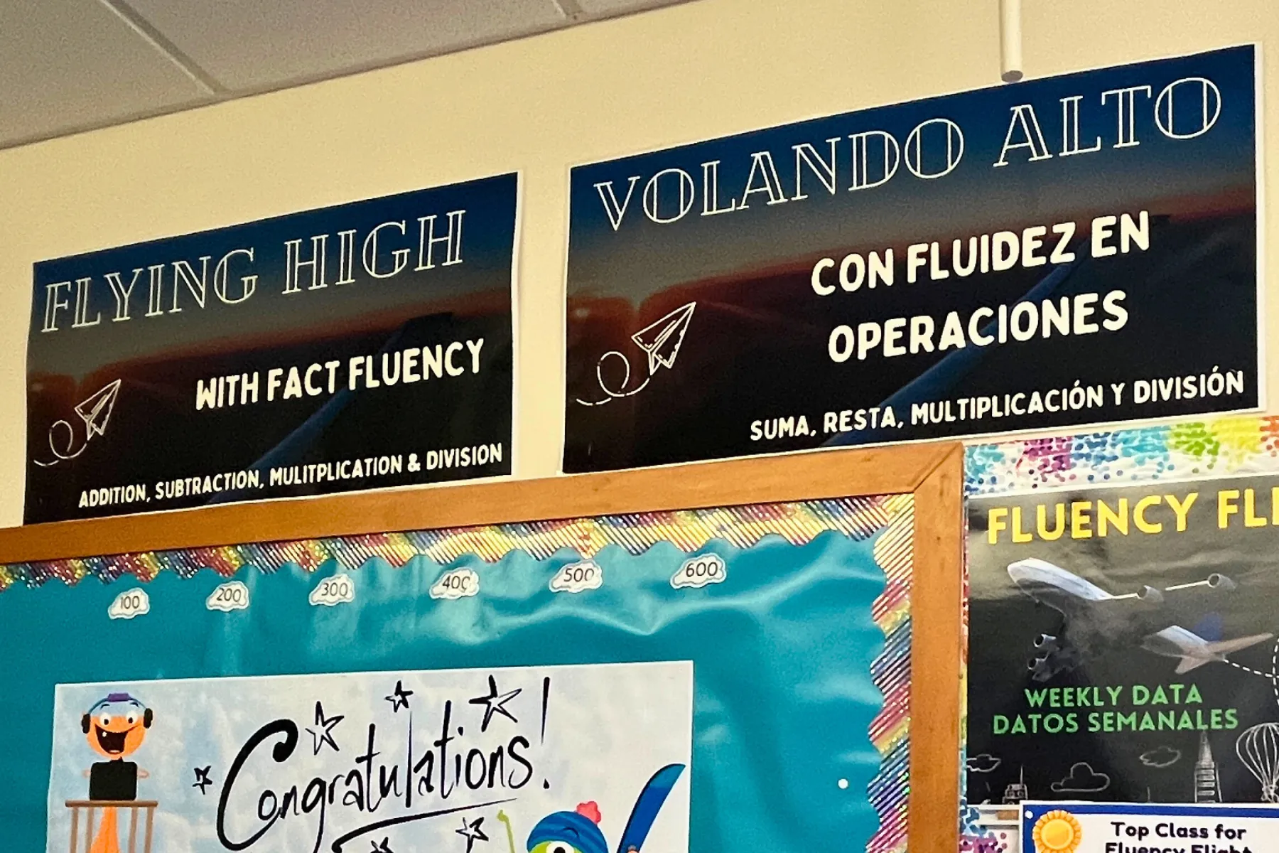 Two math posters, one in English, one in Spanish, next to each other in a school hallway.