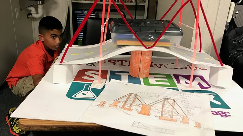 Student with a STEMvelope bridge project on a classroom table